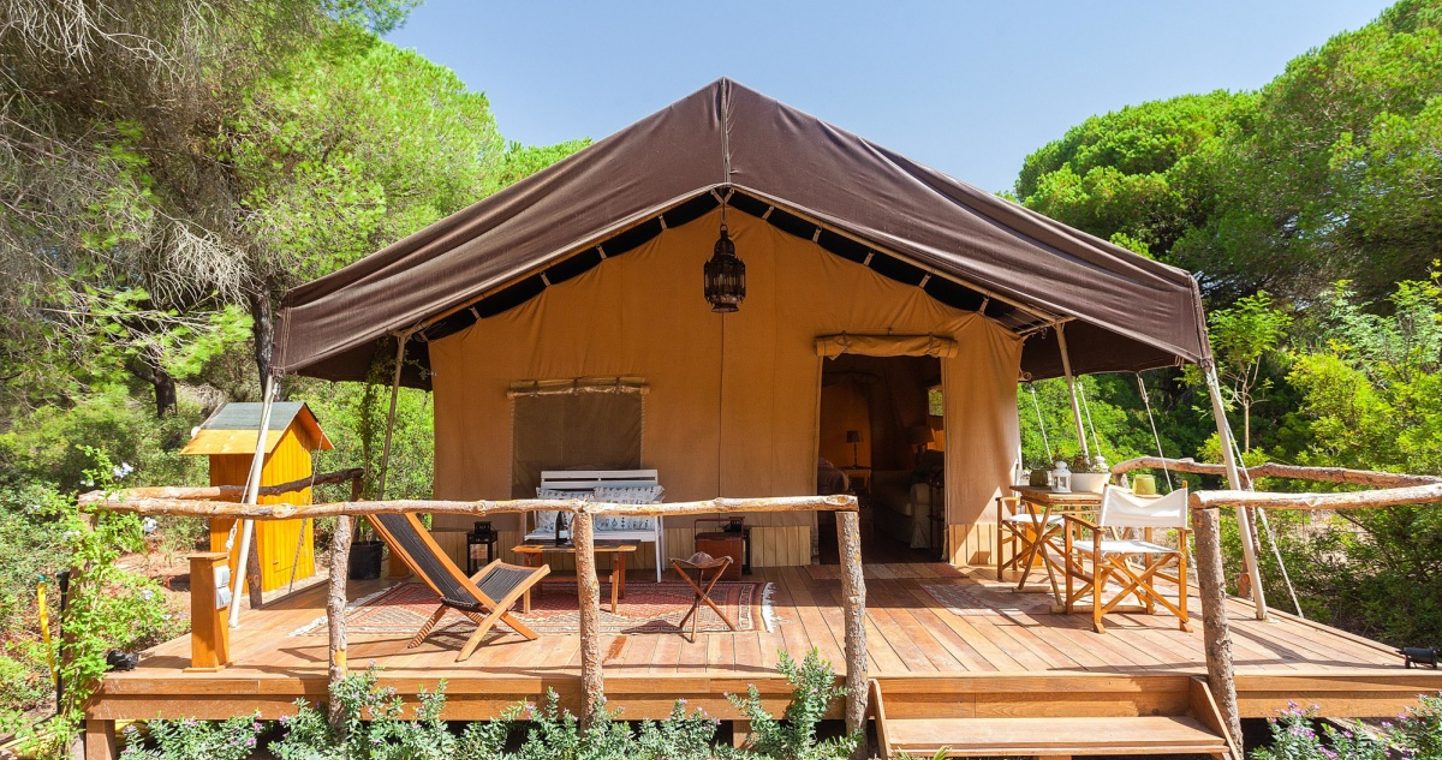 A tent surrounded by a wooden decking area with seats and deck chairs