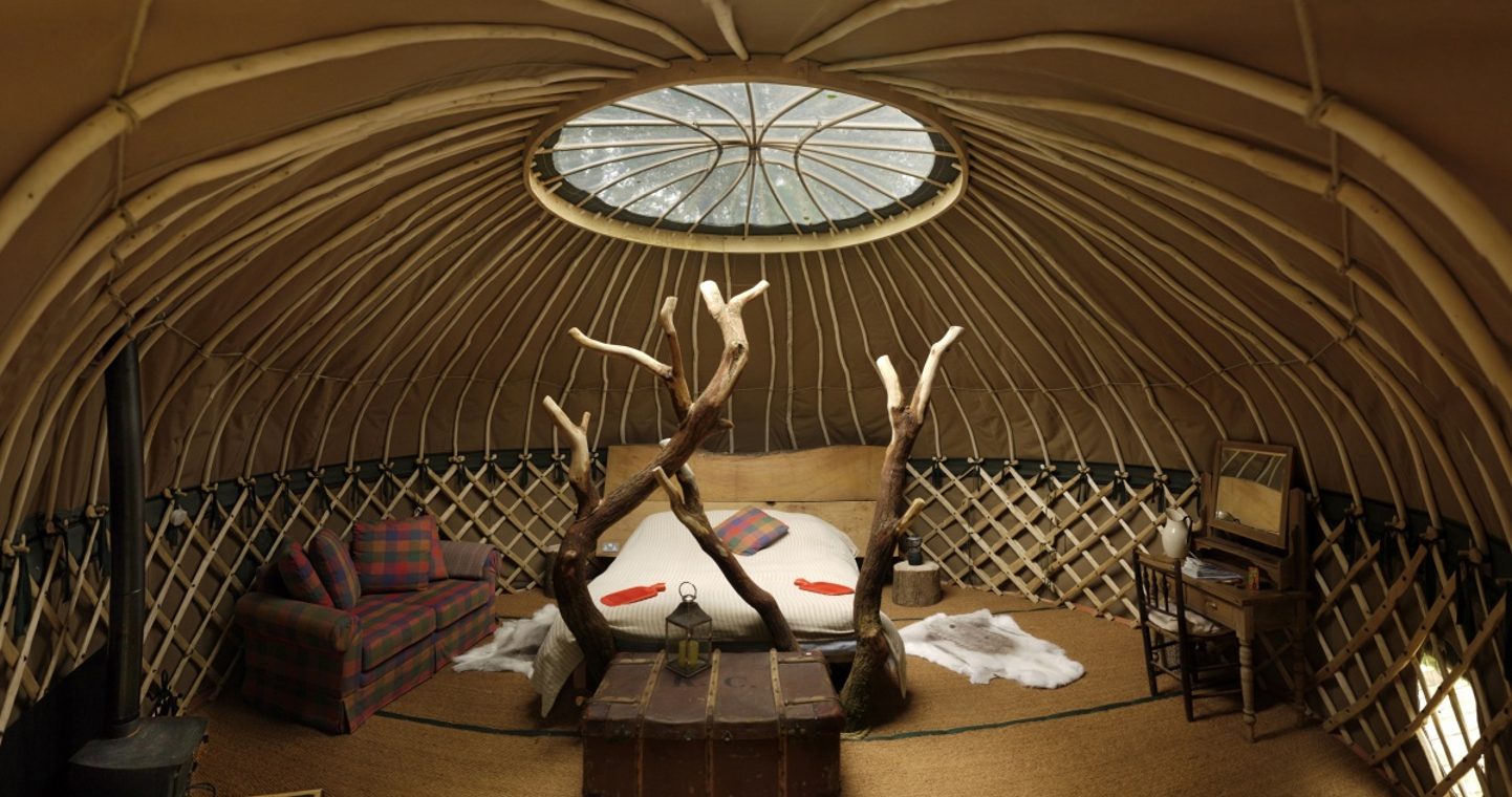 A bed with an old trunk at the foot of it, a sofa and a chair either side of it and a wood burning stove to one side