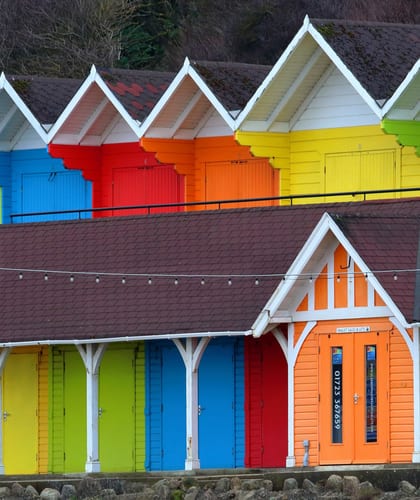 Beach houses painted different colours in the order of the rainbow