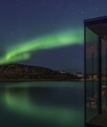 Northern lights in sky (green coloured) and reflecting on lake surface in the back ground with a square conservatory in the foreground