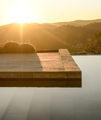 Large pool with surrounding decking area in the countryside at sunset