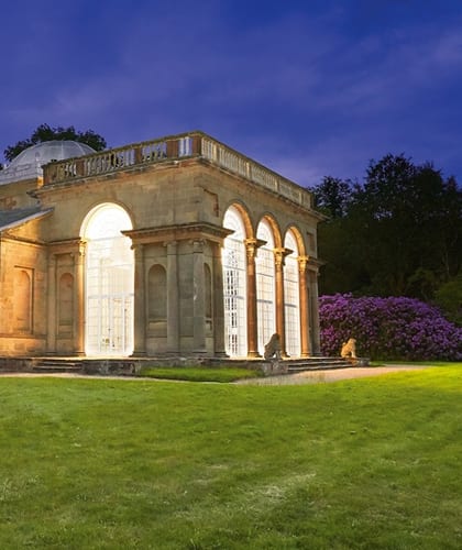 An old sandstone building with columns and archways at twilight with dark blue sky