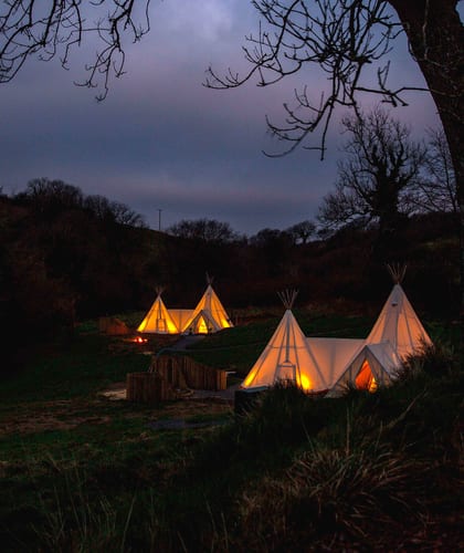 Two large tipi tents pitched on grassy rural land