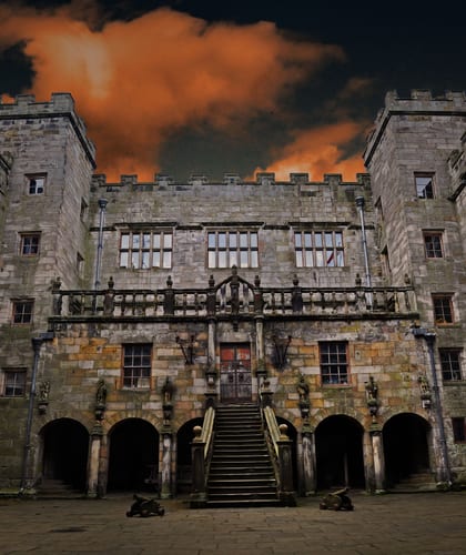 Chillingham Castle looking 'moody' at twilight with dark sky and orange clouds