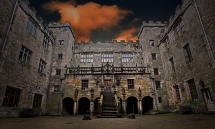 Chillingham Castle looking 'moody' at twilight with dark sky and orange clouds