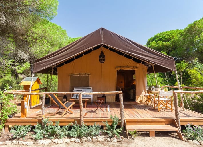A tent surrounded by a wooden decking area with seats and deck chairs