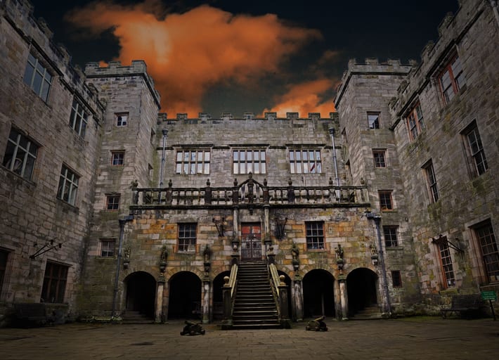 Chillingham Castle looking 'moody' at twilight with dark sky and orange clouds